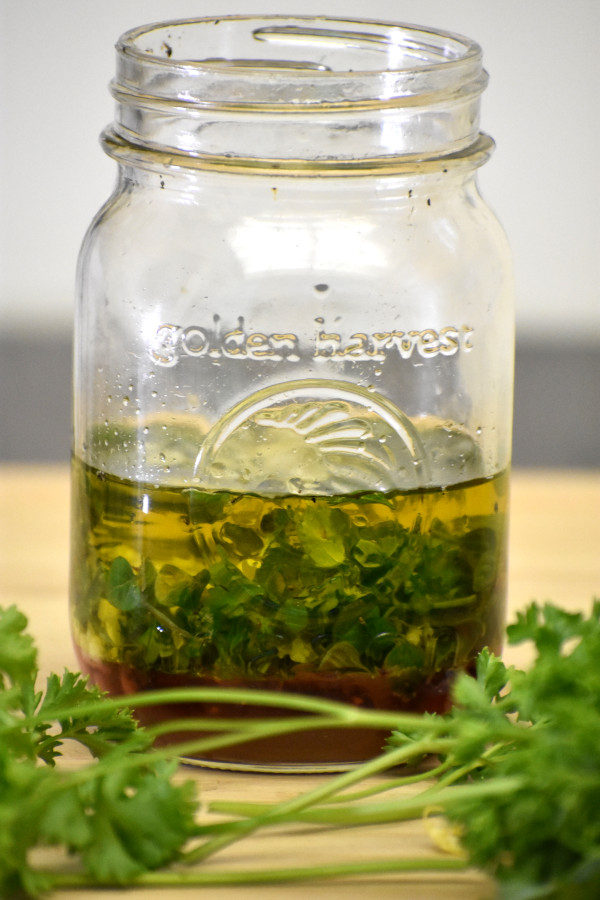 homemade salad dressing in a mason jar with fresh parsley in the foreground