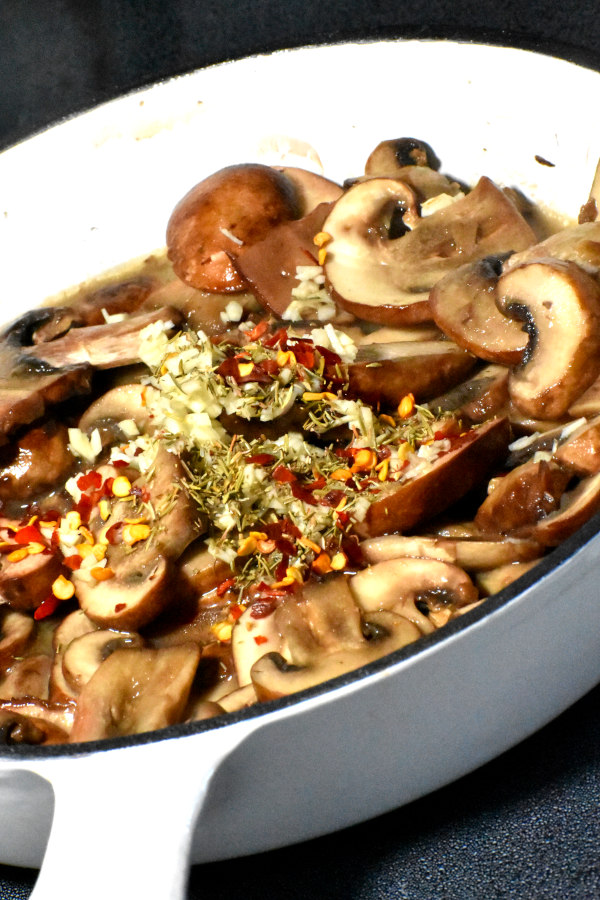 在煎锅中加入大蒜和香料煮蘑菇