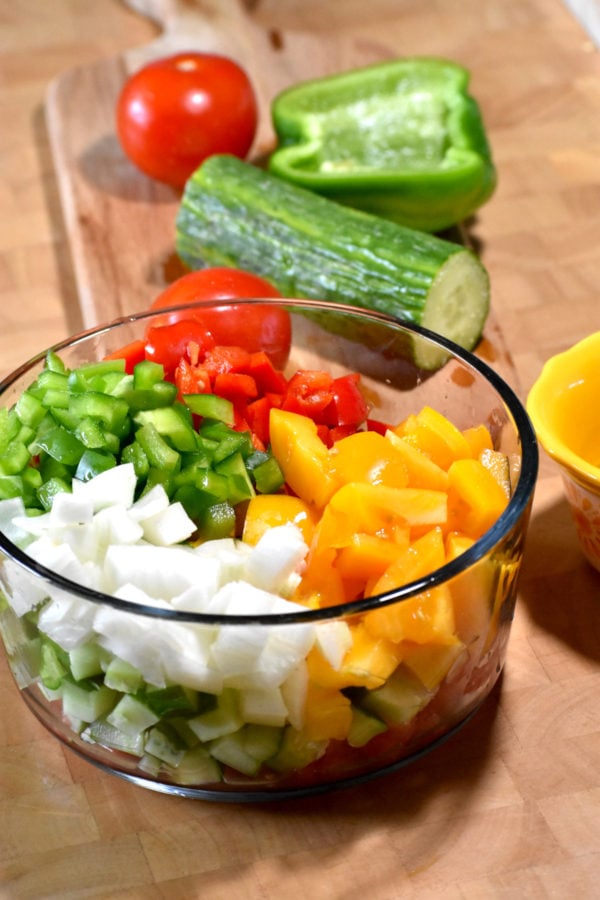 把切碎的番茄、辣椒、洋葱和黄瓜放在玻璃碗里