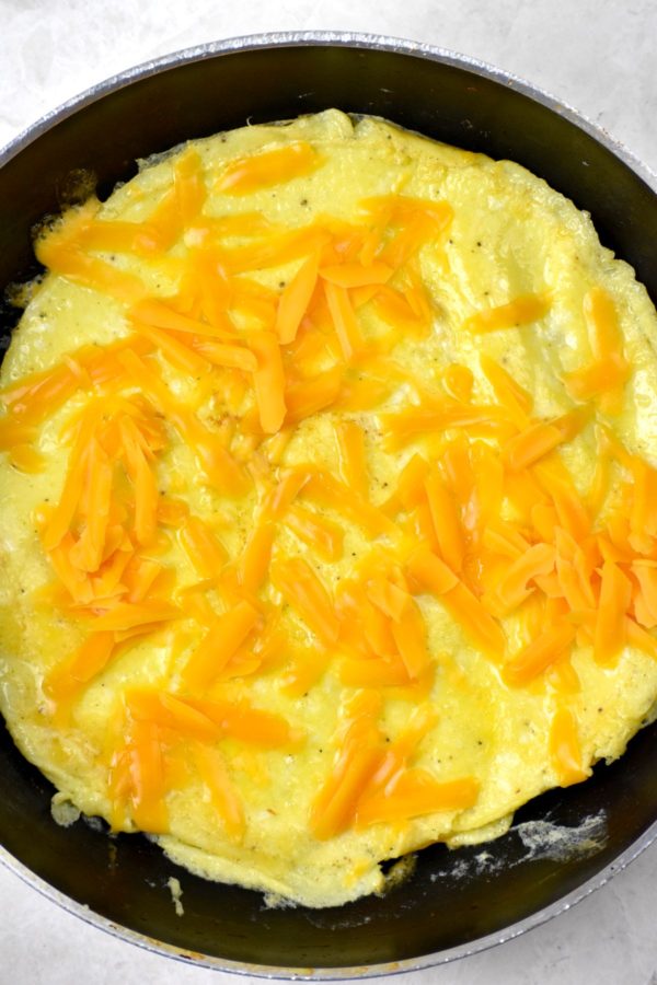 煎锅里煮熟的鸡蛋，上面撒上切碎的切达奶酪。