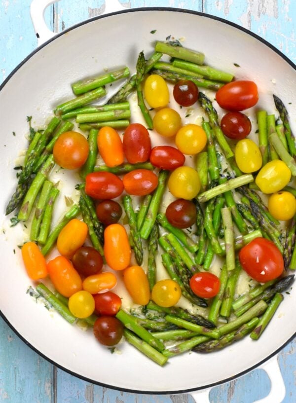cherry tomatoes and asparagus cooking in a skillet